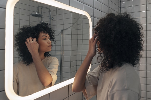 A Woman Standing In Front Of A Mirror Posing For The Camera